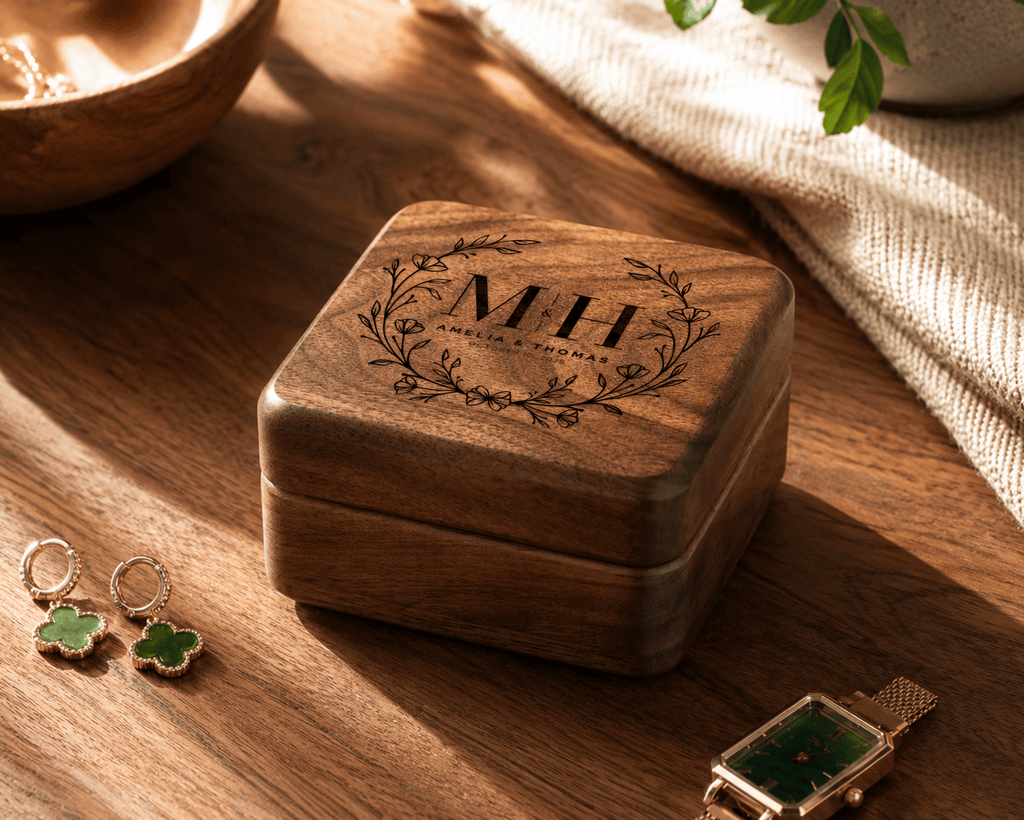 Wooden jewelry box with engraved initials on a wooden surface with earrings and a watch.