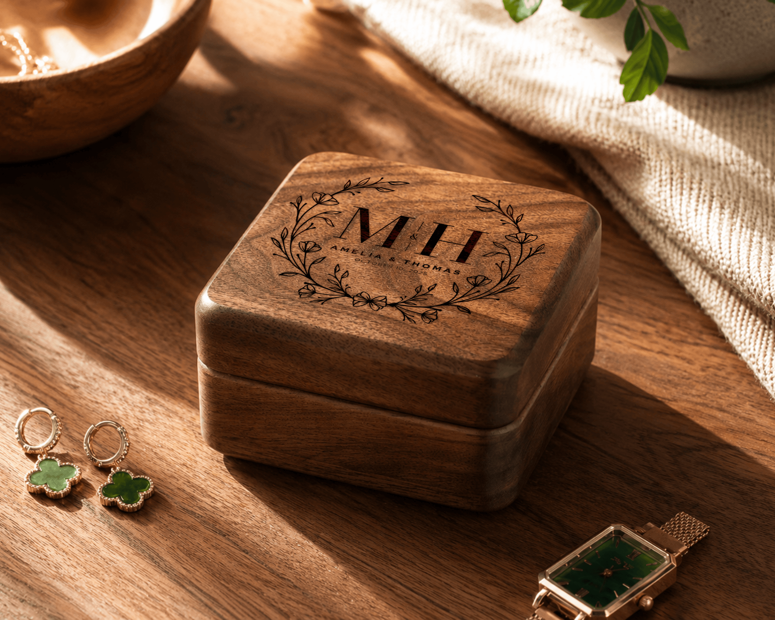 Wooden jewelry box with engraved initials on a wooden surface with earrings and a watch.