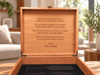 An open wooden keepsake box with a personalized engraved message on the inside lid, set on a wooden table in a softly blurred living room background.