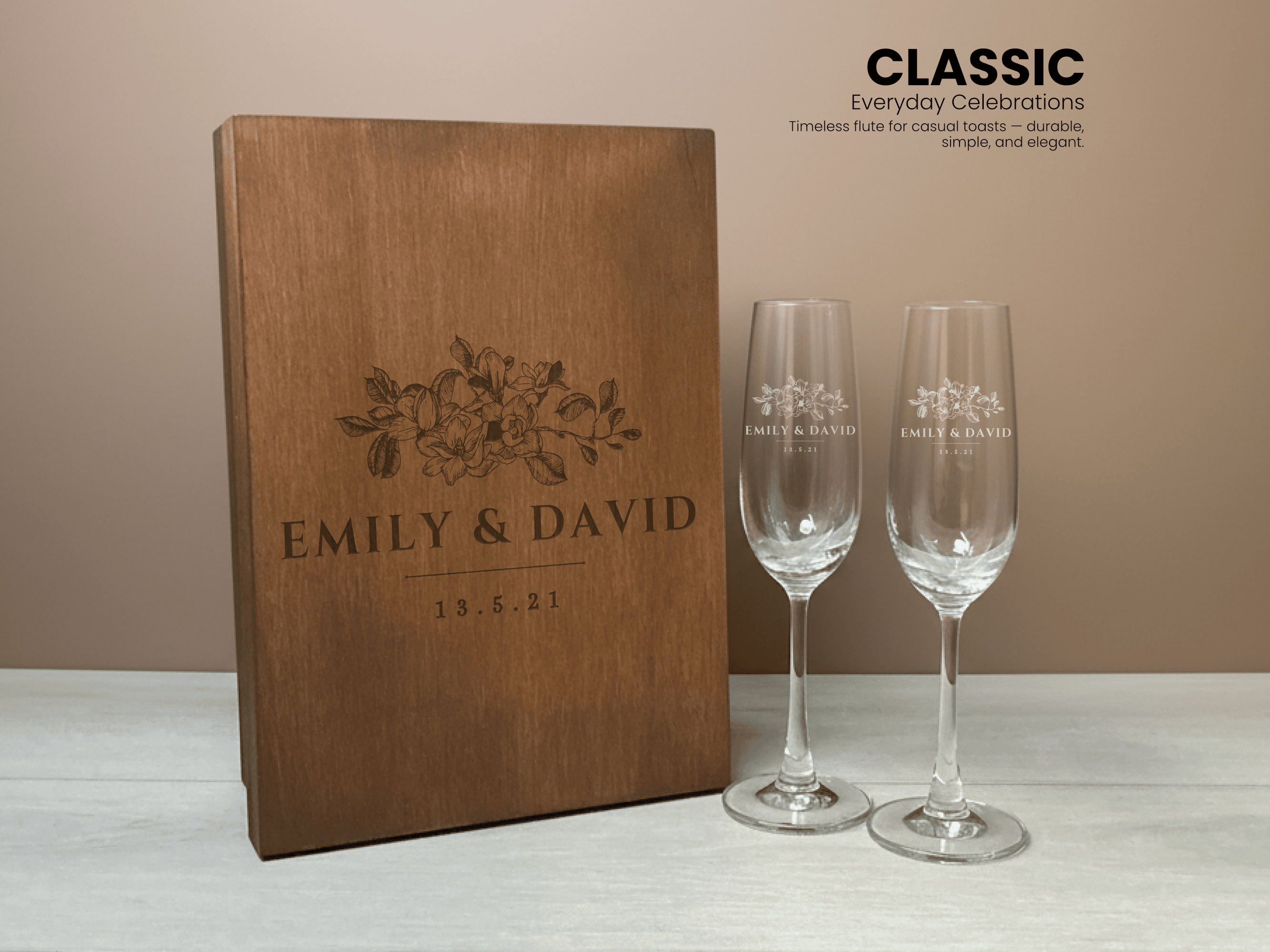 Wooden box with a custom floral design, accompanied by two classic champagne flutes on a beige background.