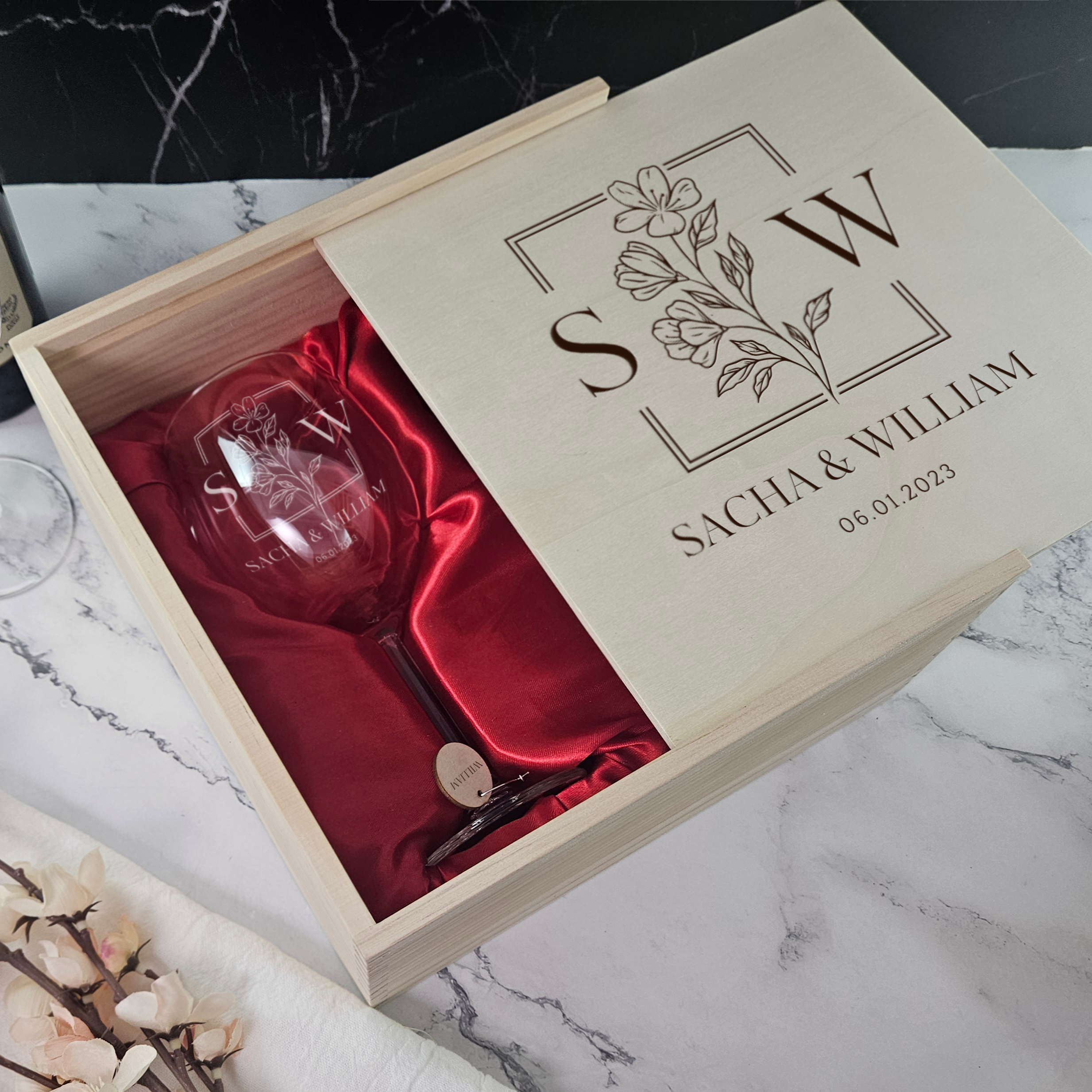 a wine glass in a box next to a bottle of wine