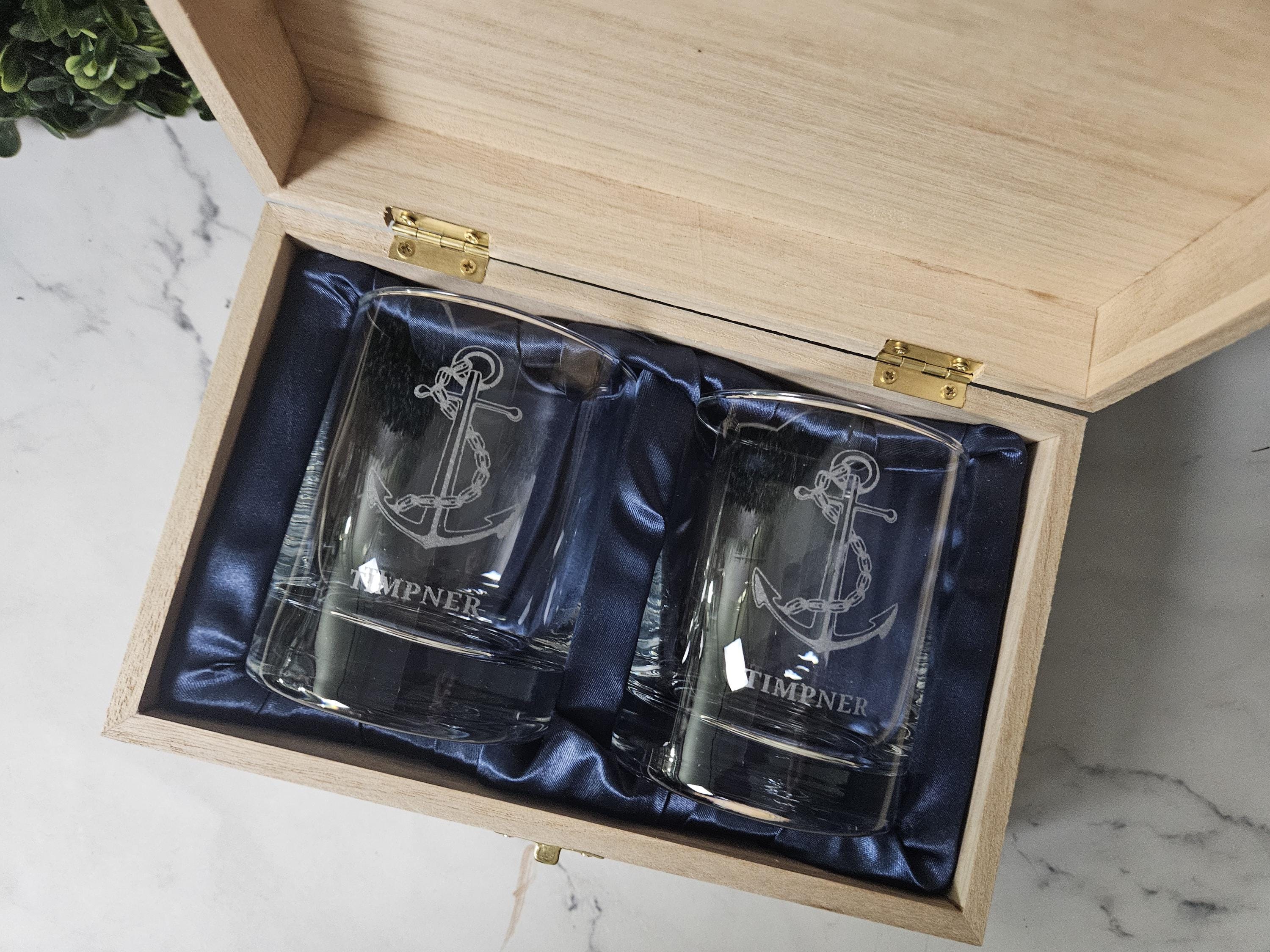 two shot glasses in a wooden box on a marble table